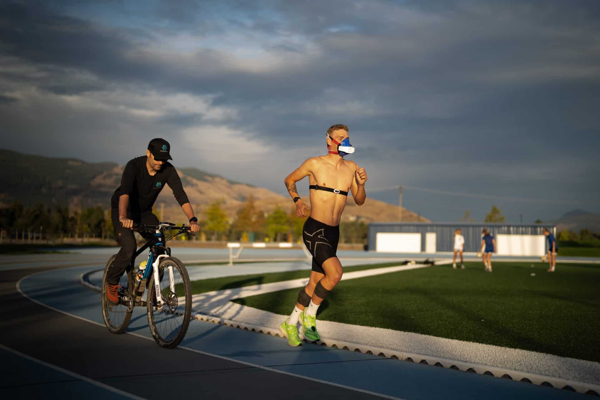 Brock Hoel is shown on the running track testing his vo2 max wearing the vo2 master analyzer. A coach follows him around the track providing real time data and training suggestions.