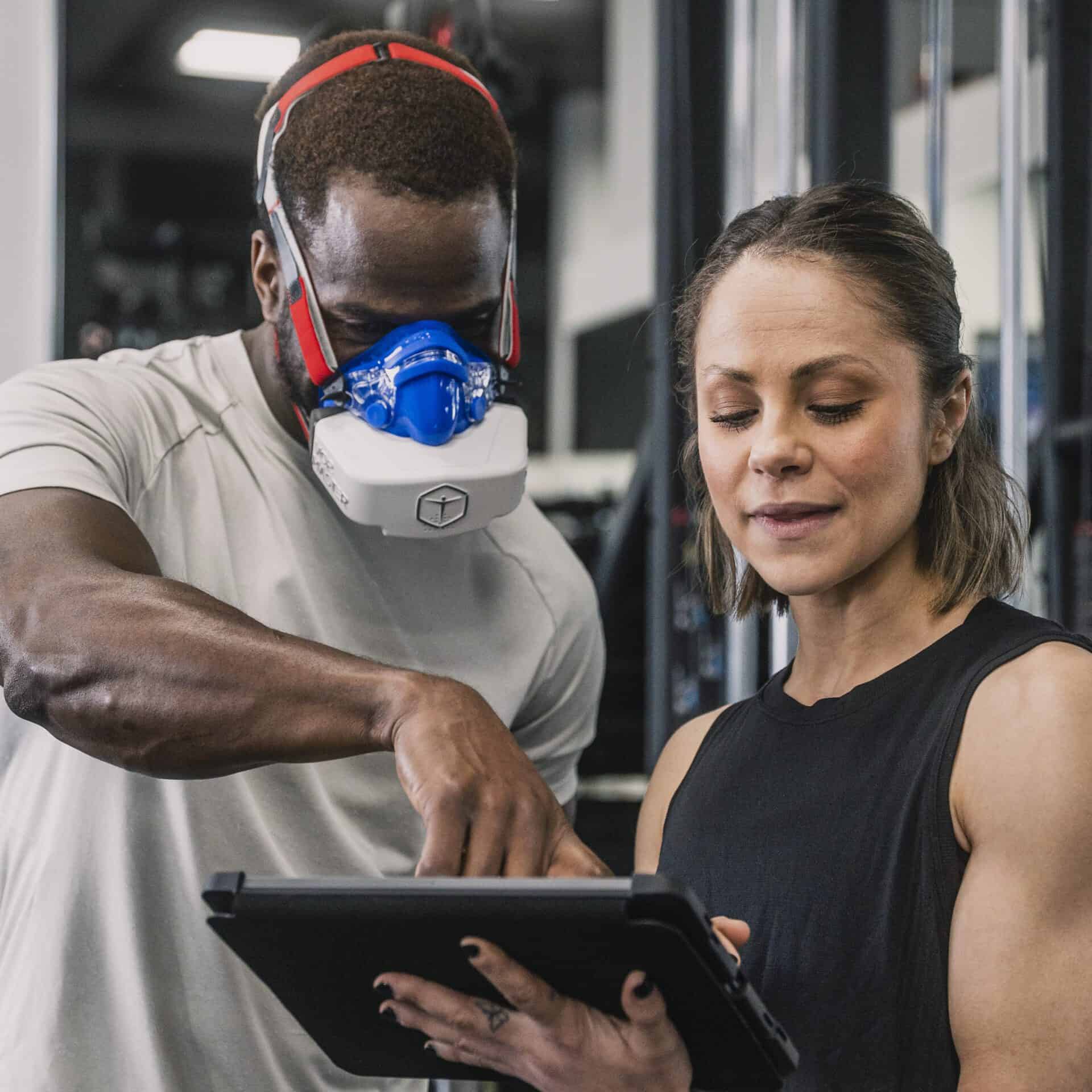 Man observing his results on the VO2 Master ipad app with female athletic coach