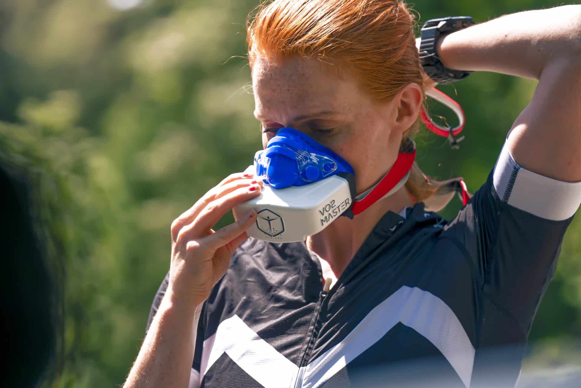 Athletic woman strapping on VO2 Master analyzer and mask outdoors