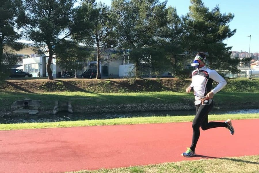 Man running on a sunny track with the analyzer mask measuring performance